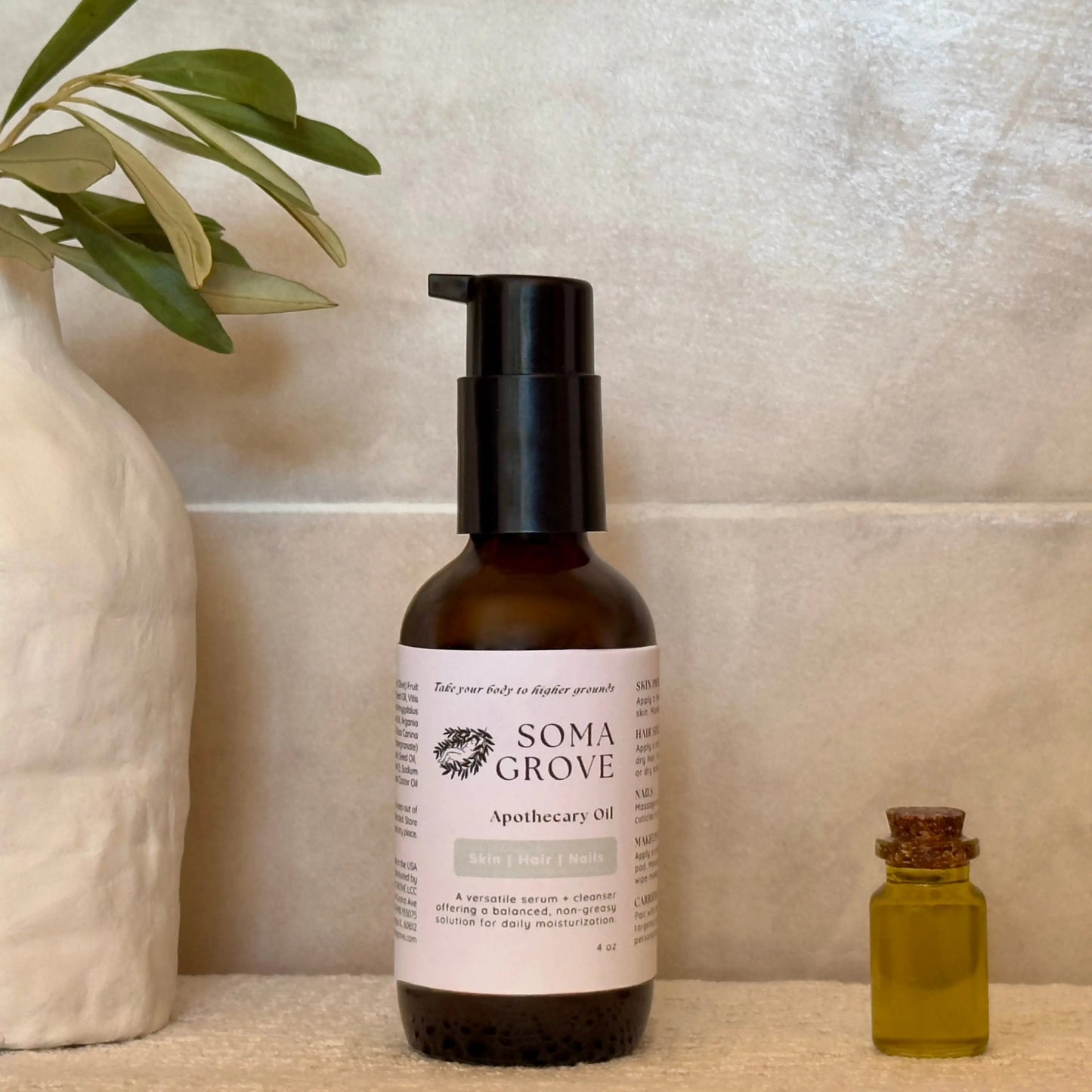 Soma Grove Apothecary Oil bottle with a test tube of olive oil and olive leaves against a neutral background.