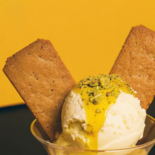 A scoop of vanilla ice cream topped with olive oil and pistachios.