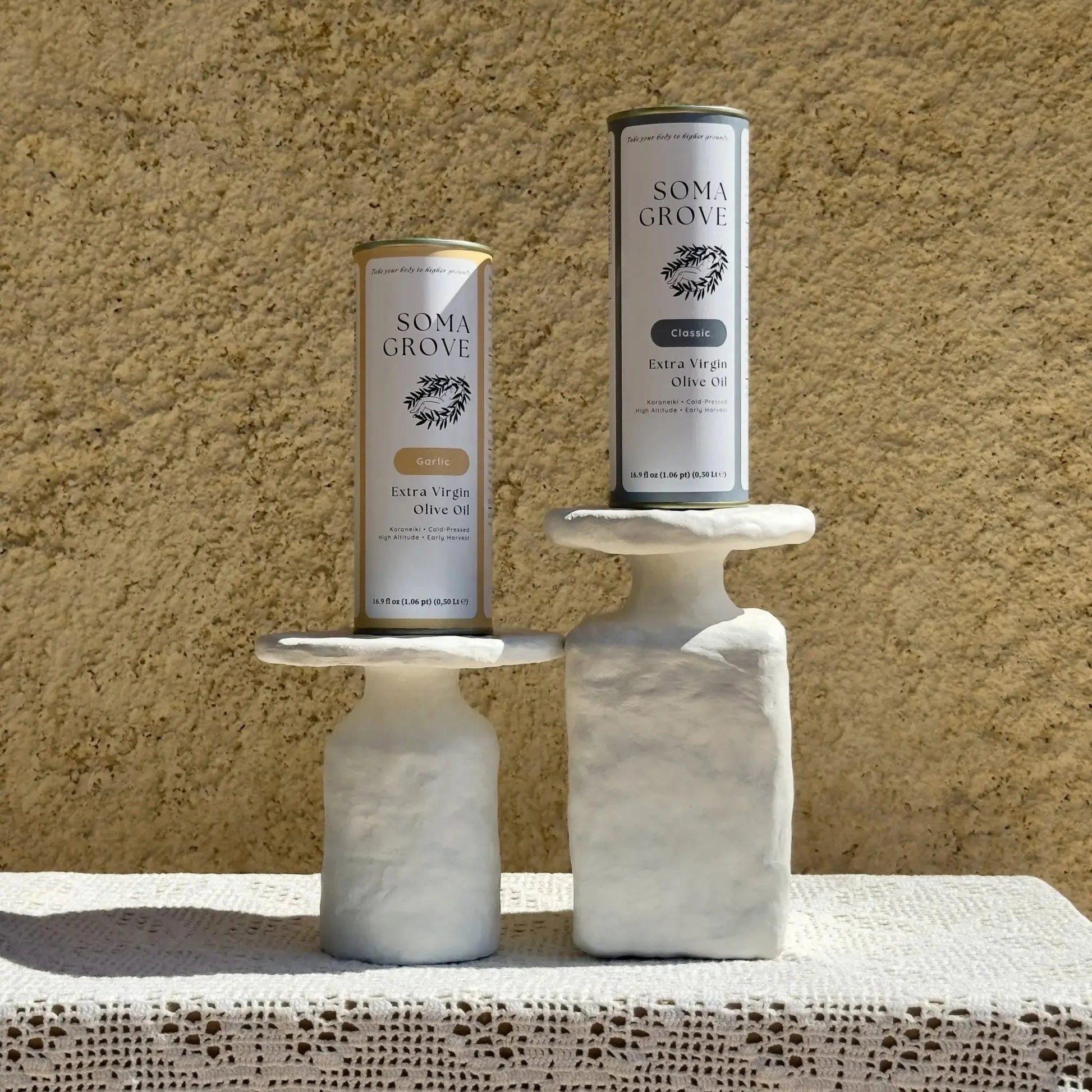 Soma Grove Garlic and Classic extra virgin olive oil bundle, featured on marble stands along a rustic setting.