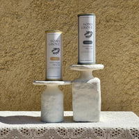 Soma Grove Garlic and Classic extra virgin olive oil bundle, featured on marble stands along a rustic setting.