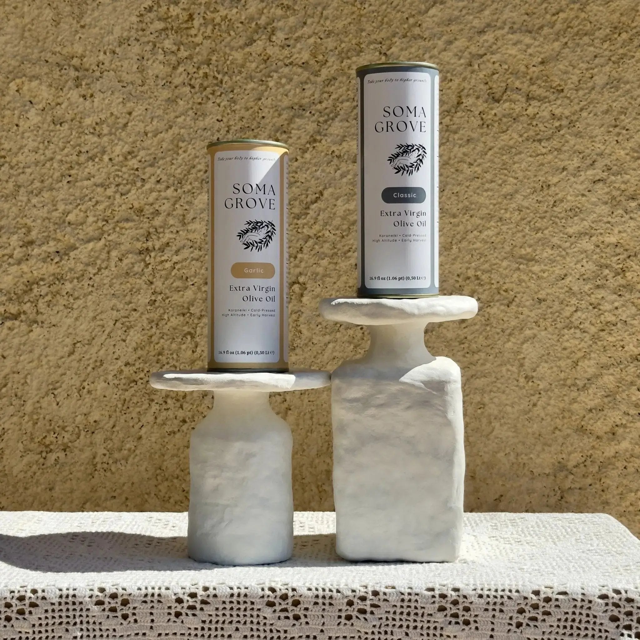 Soma Grove Garlic and Classic extra virgin olive oil bundle, featured on marble stands along a rustic setting.