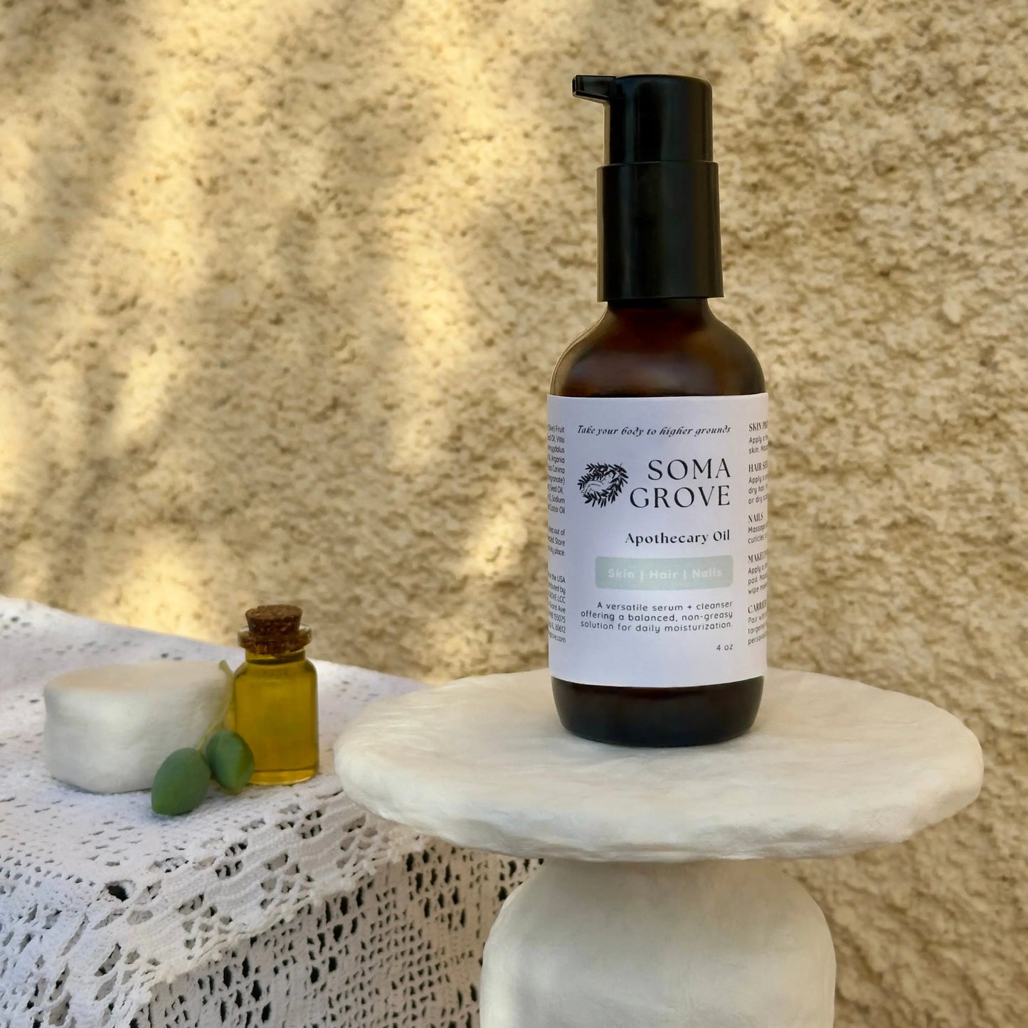 Soma Grove Apothecary Oil bottle on a marble stand with a textured beige background.